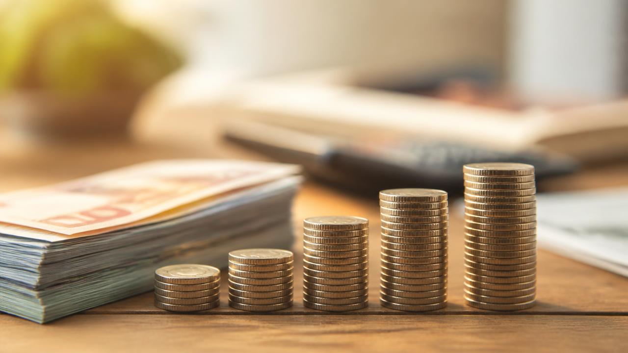 Teancuri de monede în creștere lângă bancnote, simbol al creditelor mai scumpe